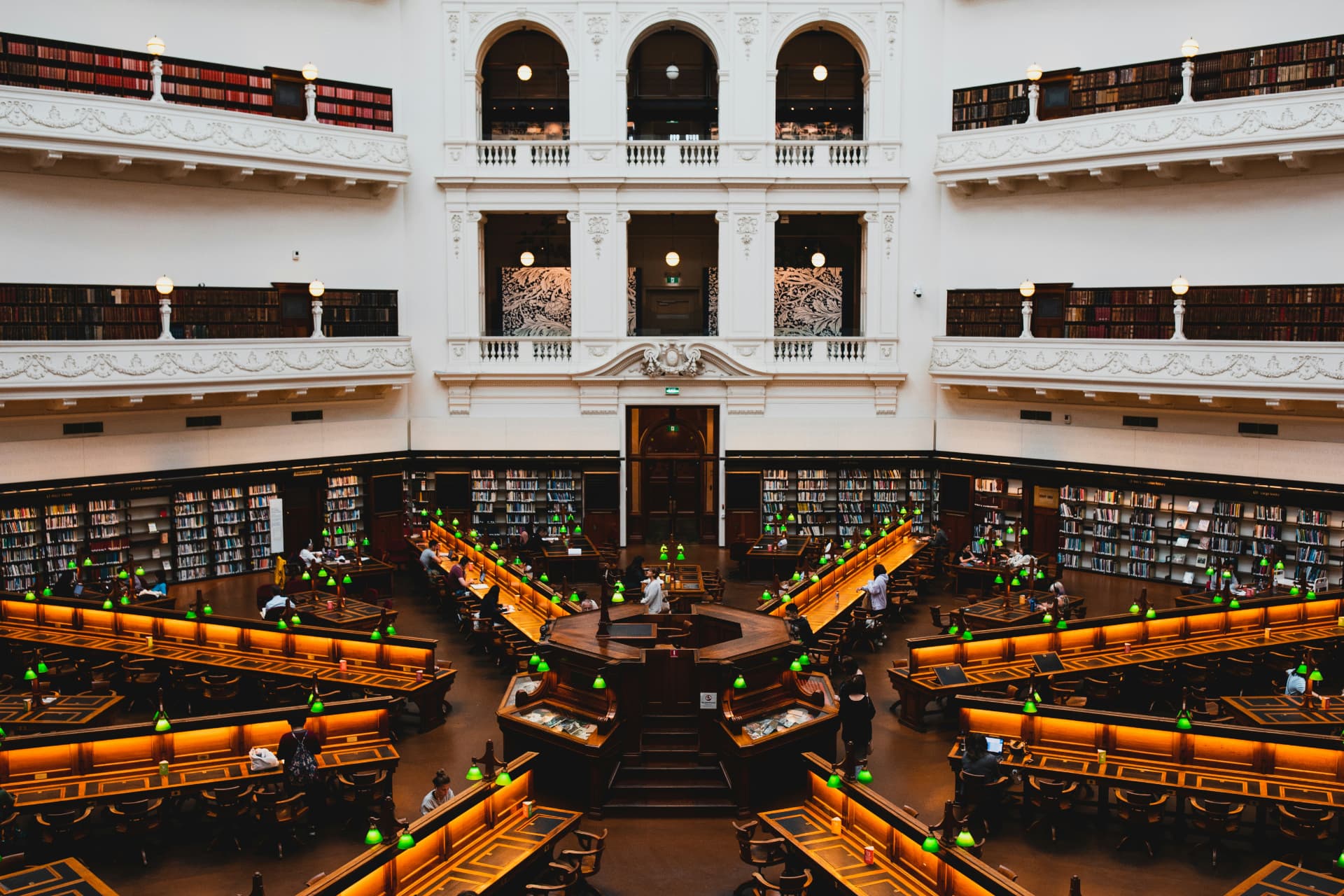 Students studying at long desks in a grand library reading room